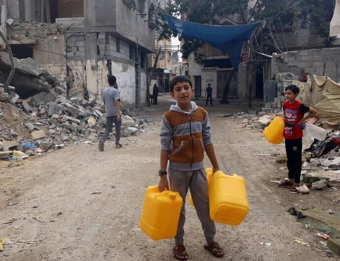 A boy collects water in a bombed neighborhood in Gaza.