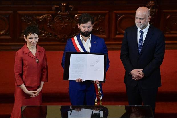 The President of Chile, Gabriel Boric, together with the Minister Secretary General of the Government, Carolina Toha, and the Secretary General of the Presidency, Álvaro Elizalde, display the signed decree that calls for a plebiscite on December 17, 2023. (Photo by Pablo VERA/AFP).